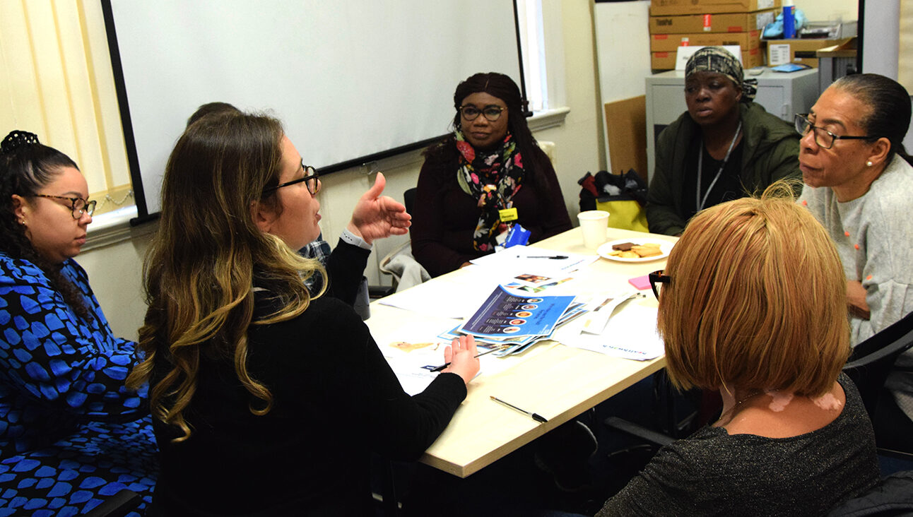 Multiple women sat around a table in the middle of a discussion