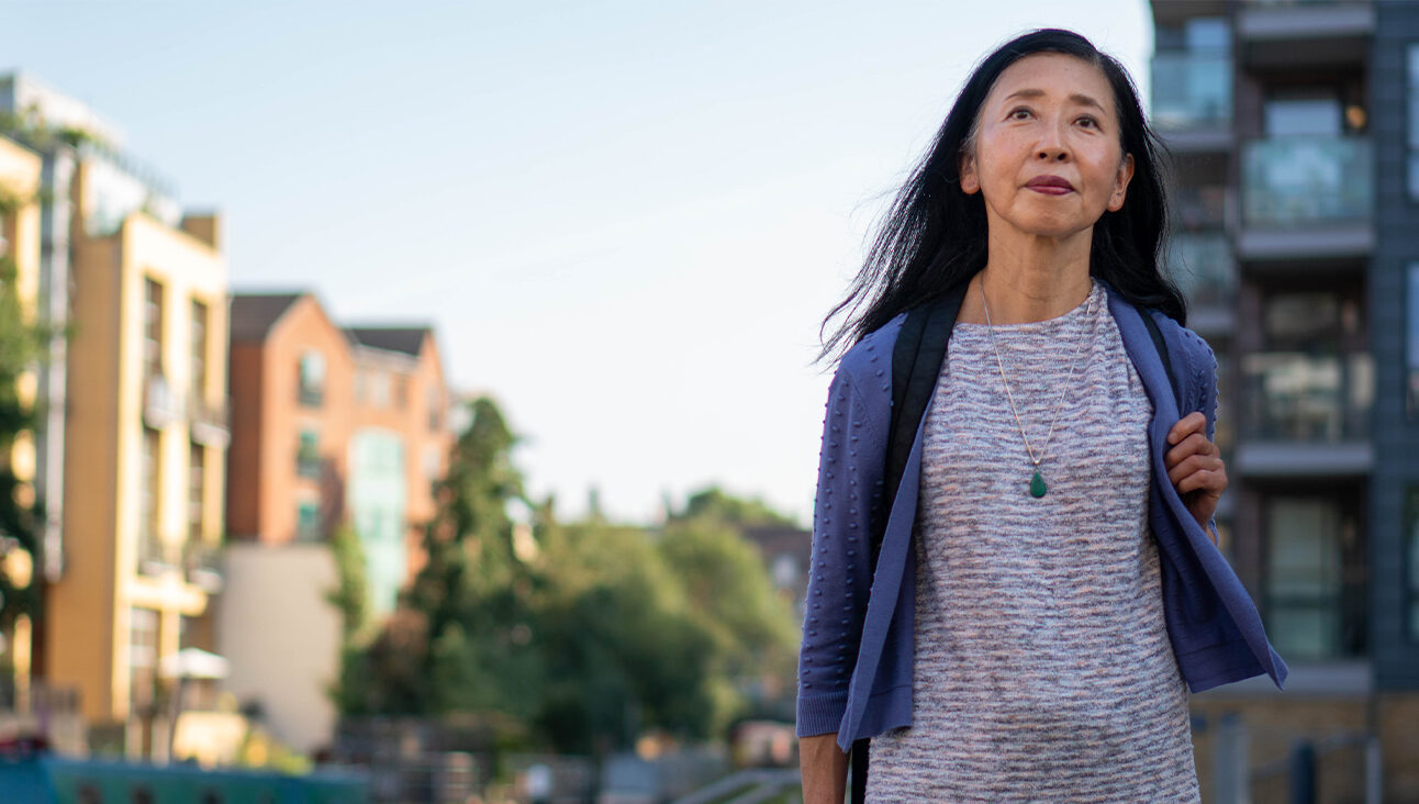 An older Asian woman walking down a street