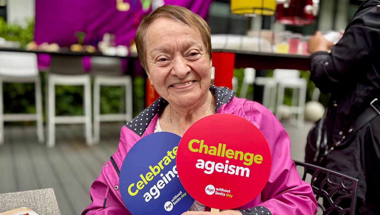 Older LATAM woman holding up two Challenge Ageism signs