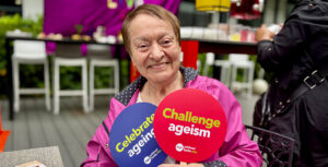 Older LATAM woman holding up two Challenge Ageism signs