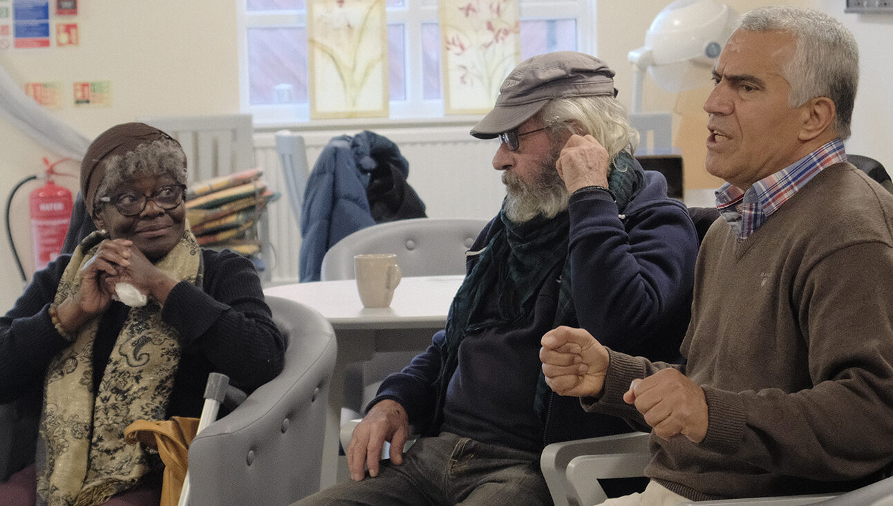 An older Black women listening to an older Turkish man at a Conversation Cafe in Haringey, London